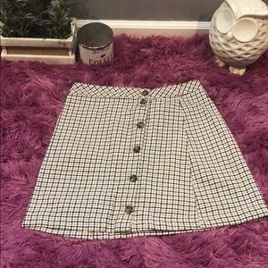 A sand tan, black, and white plaid skirt